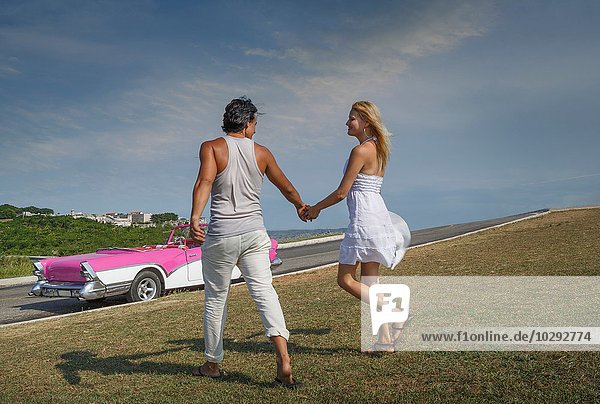 Couple holding hands  Convertible in background