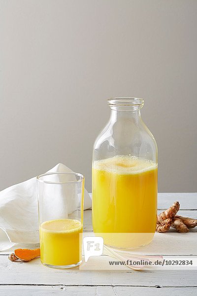 Stilleben von tumerischer Zitronengraslimonade in Trinkglas und Flasche