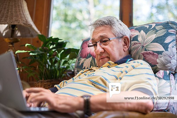 Senior Mann  zu Hause sitzend  mit Laptop