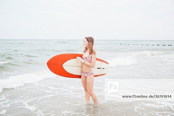 Mittlere erwachsene Frau im Meer stehend  Surfbrett haltend