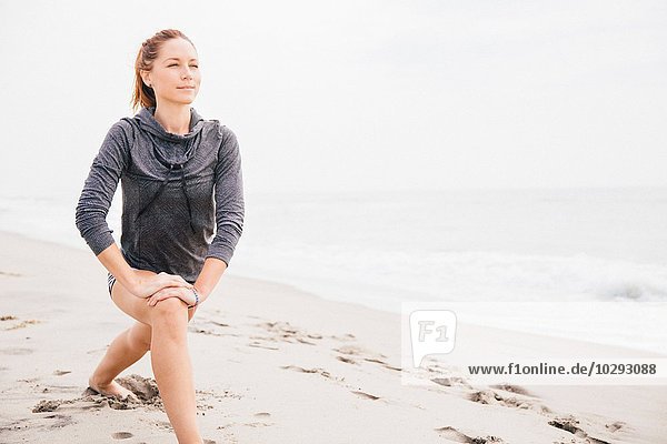 Mittlere erwachsene Frau beim Stretching am Strand