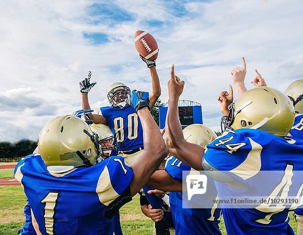 Teenager und junge männliche American Football Mannschaft feiert Sieg auf dem Fußballplatz