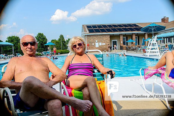 Porträt eines lächelnden Seniorenpaares am Swimmingpool