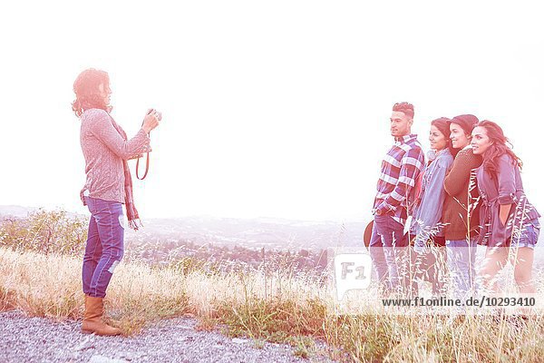 Junge Frau fotografiert ihre vier erwachsenen Geschwister auf einem Hügel auf dem Land