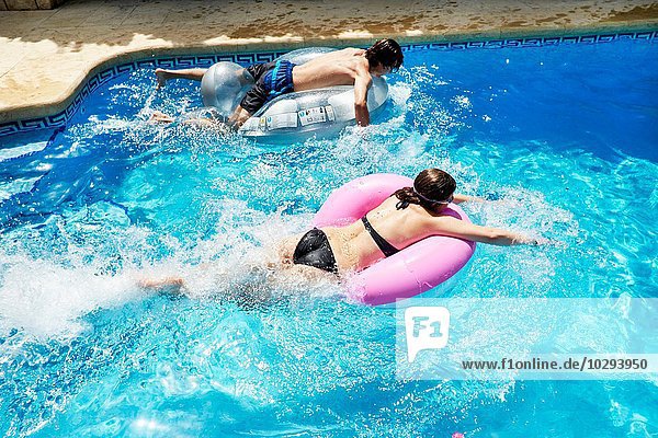 Junger Mann und jugendliche Schwester auf Hüpfburgen im Schwimmbad