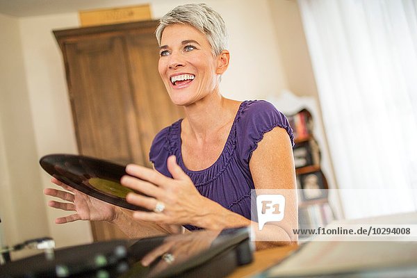Fröhliche reife Frau beim Spielen von Schallplatten