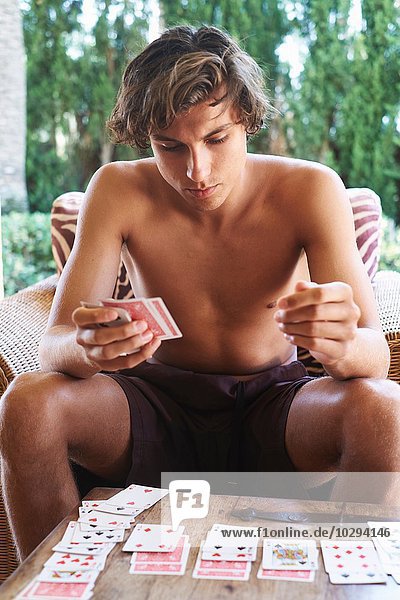 Junger Mann beim Kartenspielen am Terrassentisch