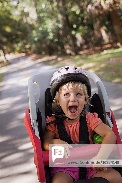 Young girl sitting in child's bicycle seat  enjoying journey