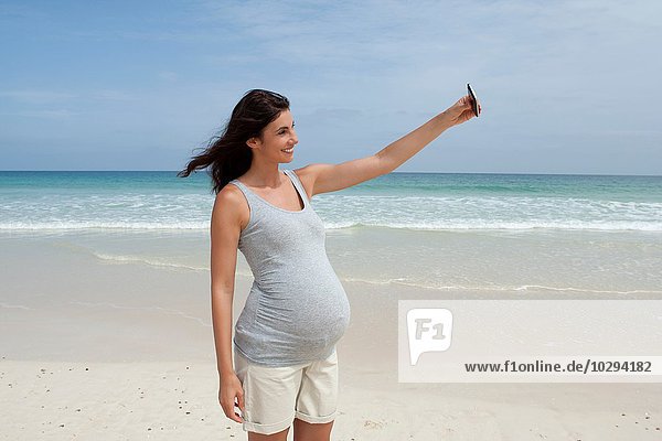 Schwangere mittlere erwachsene Frau nimmt Selfie auf Smartphone am Strand  Kap Verde  Afrika