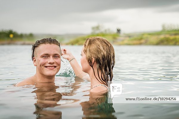 Portrait of young couple splashing in Secret Lagoon hot spring (Gamla Laugin)  Fludir  Iceland