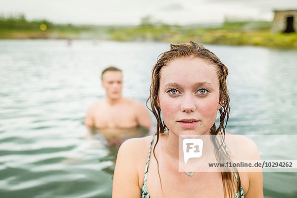 Portrait of young woman standing in front of boyfriend in Secret Lagoon hot spring (Gamla Laugin)  Fludir  Iceland