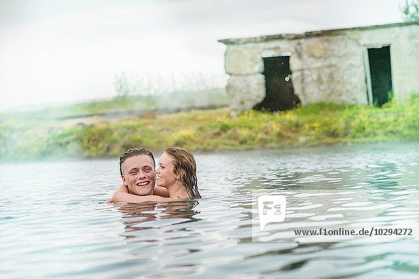Young couple hugging in Secret Lagoon hot spring (Gamla Laugin)  Fludir  Iceland