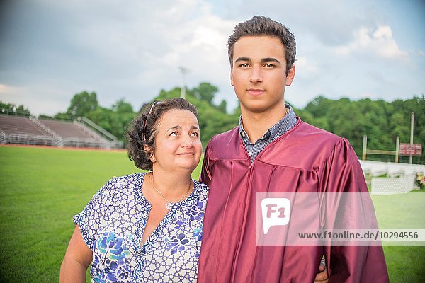 Junger Mann stehend mit Mutter bei der Abschlussfeier