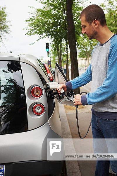 Mann lädt Elektroauto auf der Straße  Paris  Frankreich