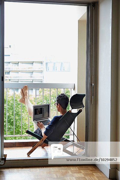 Woman using laptop on balcony