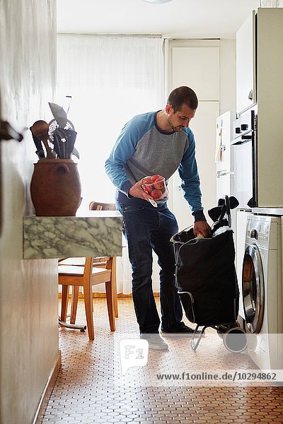 Man unpacking groceries at home