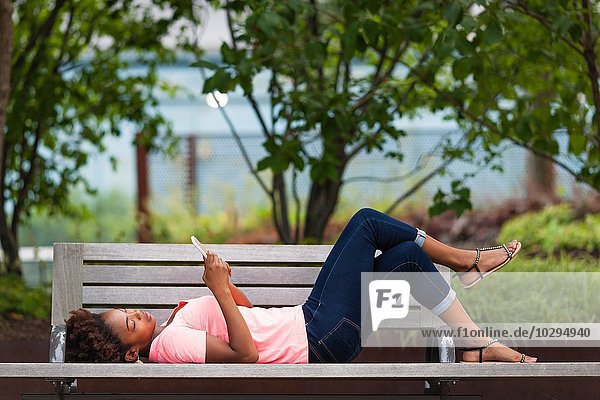 Young woman using smartphone on park bench