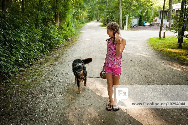 Front view of girl on dirt road  walking dog  looking over shoulder