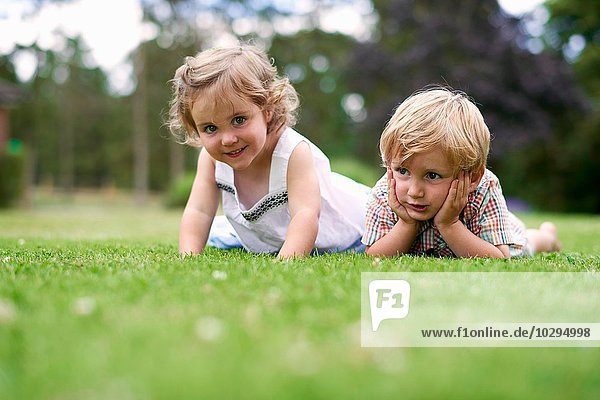 Surface level of boy and girl lying on grass