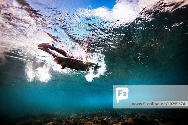 Underwater view of surfer paddling through ocean to catch waves in Bali  Indonesia
