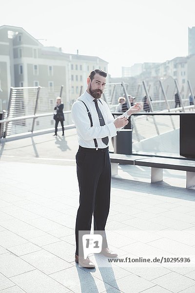 Portrait of stylish businessman fastening shirt cuffs on footbridge