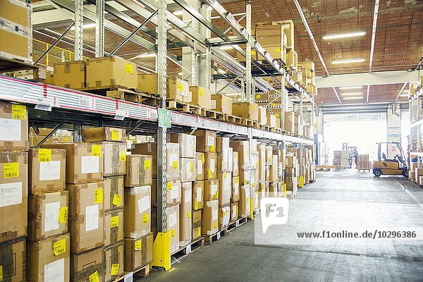 Forklift trucks working in distribution warehouse aisle