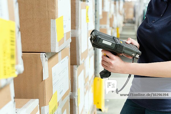 Cropped view of warehouse worker using barcode scanner on box in distribution warehouse