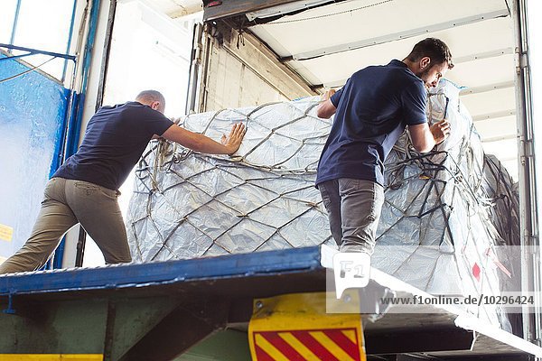 Arbeiter schieben Fracht in Luftfrachtcontainer