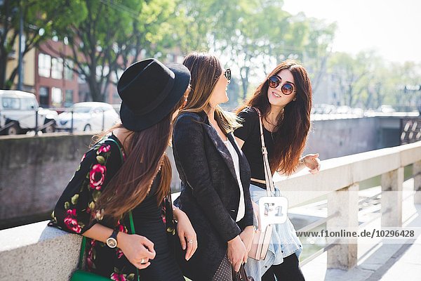 Drei junge Freundinnen beim Plaudern am Flussufer der Stadt