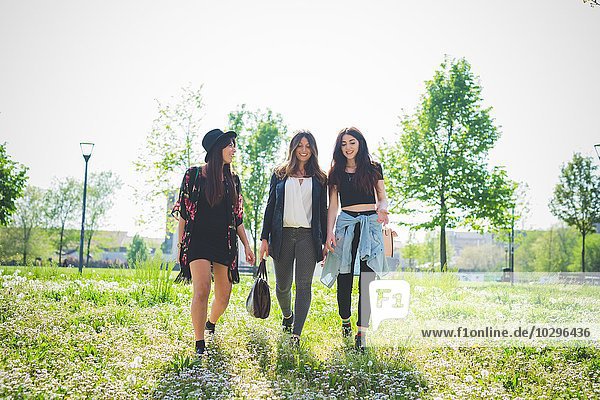 Three young female friends strolling in park