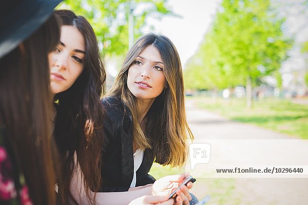 Drei junge Freundinnen beim Gespräch im Park