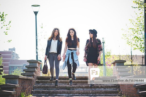 Drei junge Freundinnen schlendern die Parktreppe hinunter.