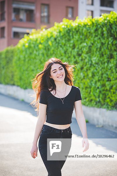 Schöne junge Frau mit langen braunen Haaren beim Spazierengehen