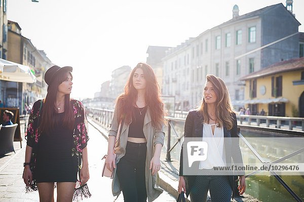 Drei junge stilvolle Frauen schlendern auf Kanal am Wasser