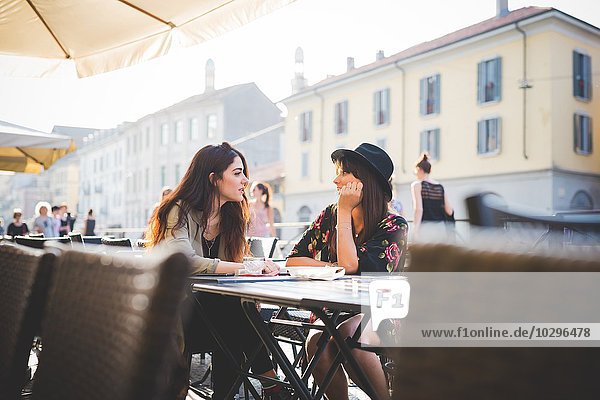 Two young women chatting at sidewalk cafe