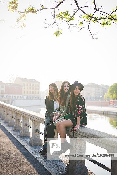 Porträt von drei jungen Frauen  die am Ufer des Kanals sitzen
