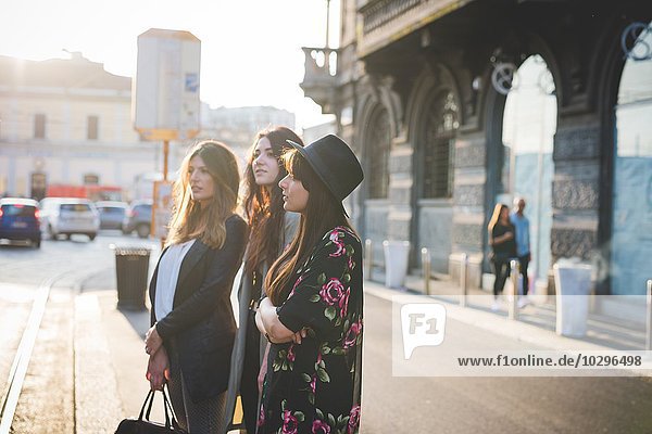 Drei junge Frauen warten auf der Stadtstraße