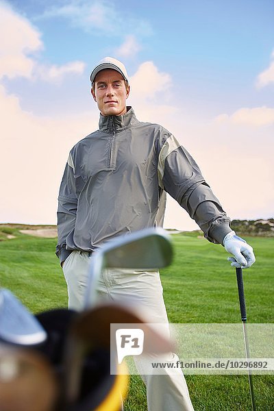 Golfer mit Golfschläger  Hand in Tasche  Blick in die Kamera
