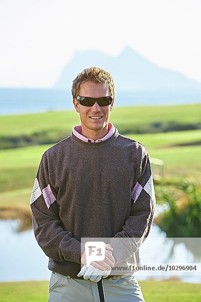 Golfer mit Sonnenbrille beim Anblick der Kamera lächelnd