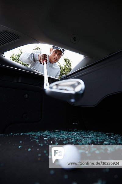 Golfer mit Golfschläger  um einen Golfball durch ein zerschmettertes Autofenster zu holen