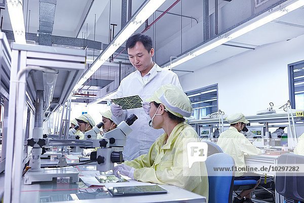 Supervisor overseeing quality check station at factory producing flexible electronic circuit boards. Plant is located in the south of China  in Zhuhai  Guangdong province