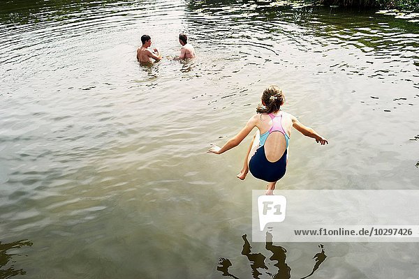 Rear view of girl jumping into lake