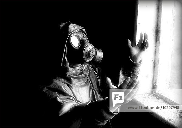 Person with gas mask looking into the bright light  creative image  worshiping the Midnight Sun of a nuclear strike
