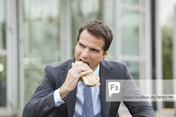 Geschäftsmann beim Sandwichessen im Freien