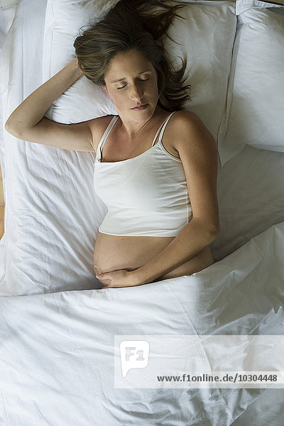Schwangere Frau schläft im Bett