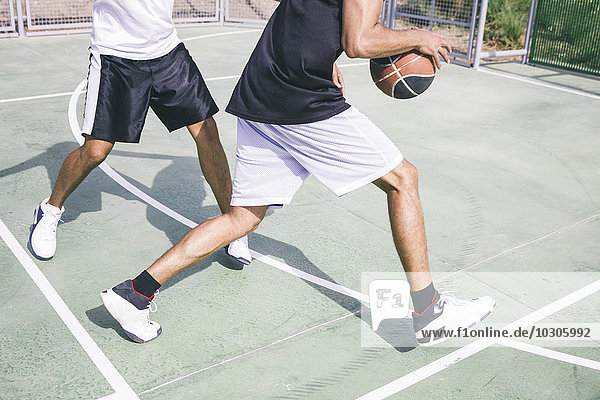 Junge Männer spielen Basketball