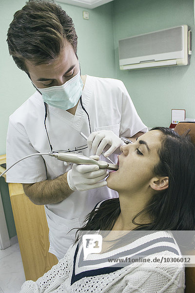 Zahnarzt bei der Untersuchung des Mundes eines Patienten mit einer Intraoralkamera