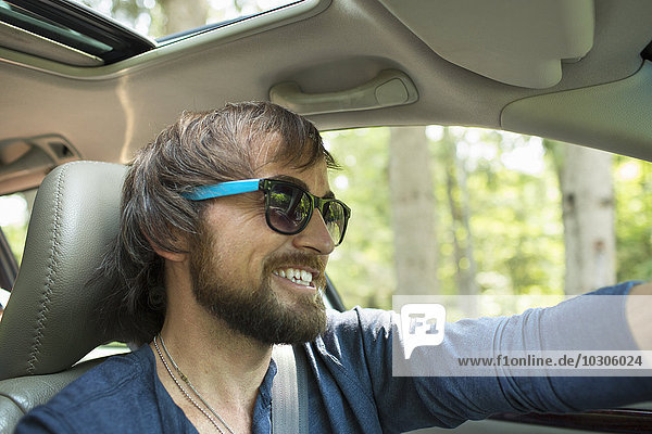 A man in sunglasses in the driving seat of a car.