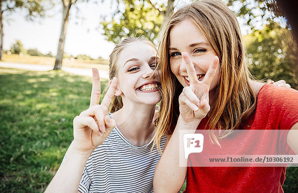 Zwei verspielte Teenager-Mädchen machen Siegeszeichen