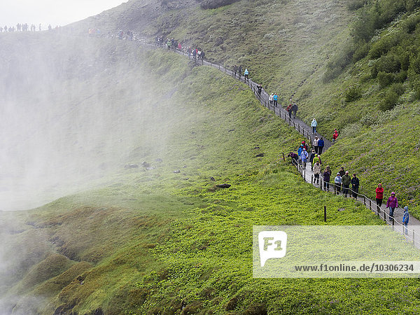 Wanderer auf dem Weg zum Gullfoss-Wasserfall. Nebel  der aus der Schlucht aufsteigt.